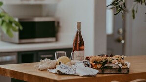 Une table de salle à manger en bois, avec une bouteille de vin, des verres et un dessert.