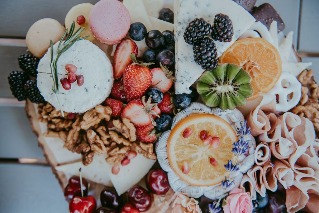 A charcuterie board with various cheeses, fruits, and nuts.