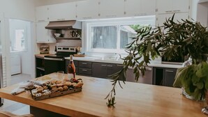 Une cuisine moderne avec des meubles blancs, un plan de travail en bois et une fenêtre qui laisse entrer la lumière naturelle.