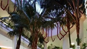 Ein mehrgeschossiges Atrium mit Palmen, einem Wasserspiel und verschiedenen Pflanzen.