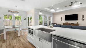 A modern kitchen with a large island, stainless steel appliances, and pendant lighting.
