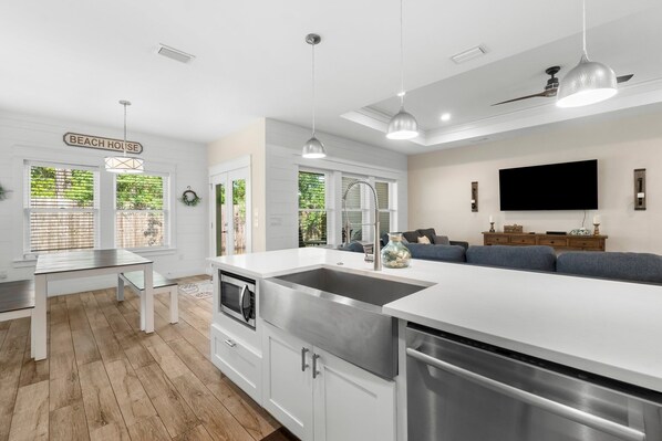 A modern kitchen with a large island, stainless steel appliances, and pendant lighting.