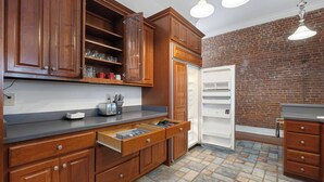 Una cocina con armarios de madera, horno empotrado y pared de ladrillo.