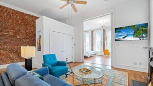 Una sala de estar moderna con una pared de ladrillo, un sillón azul, una mesa de centro de vidrio y una chimenea.