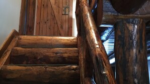 Una escalera de madera con barandilla que lleva a una puerta de madera.