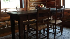 Un comedor rústico de madera con una mesa grande y sillas, una araña y una obra de arte enmarcada en la pared.