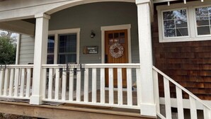 A house with a porch, a wooden door, and a welcome sign.