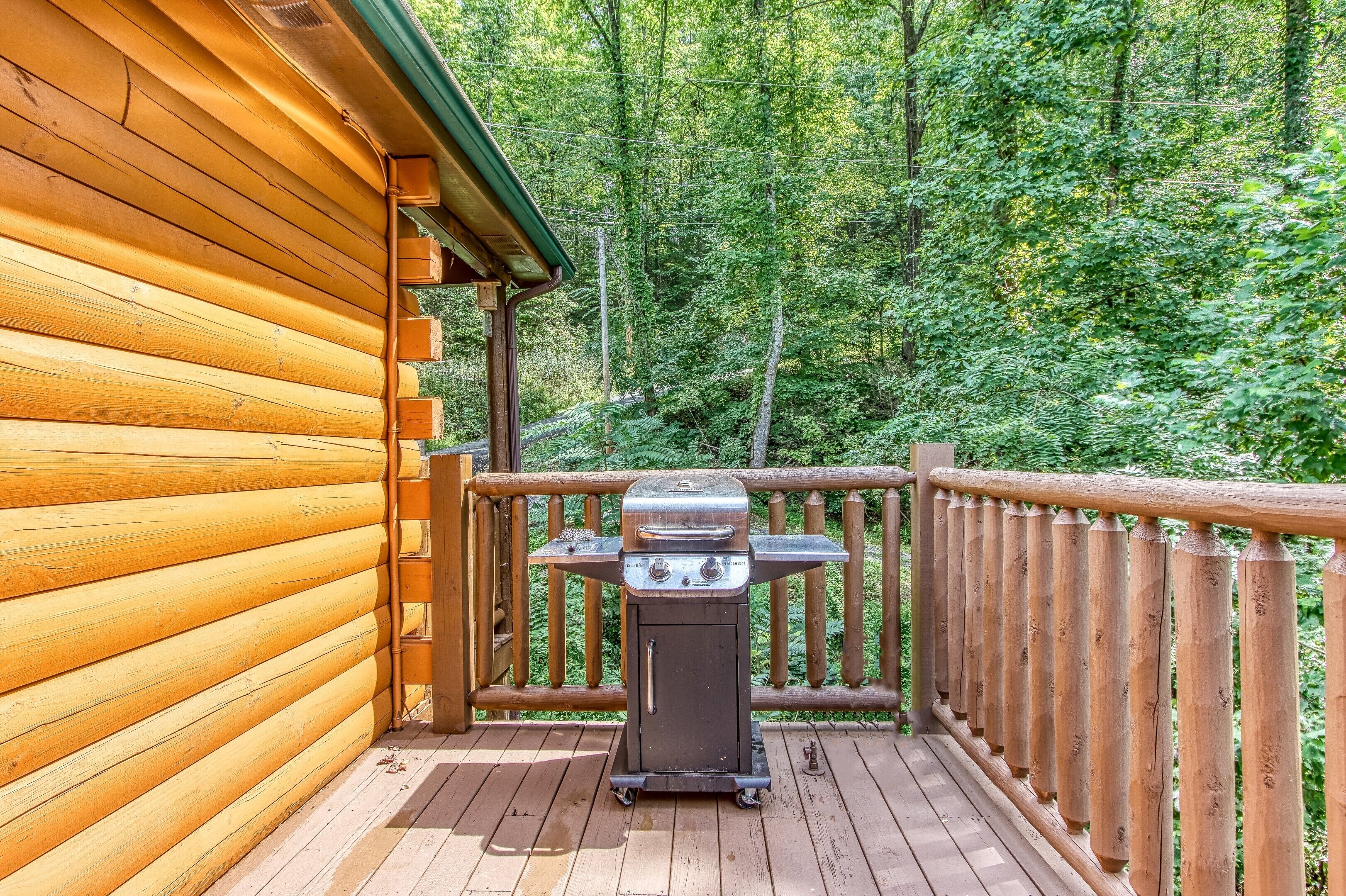 A wooden deck with a barbecue grill and a wooden cabin in the background.