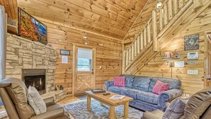 L’intérieur d’un chalet confortable, avec une cheminée en pierre, un canapé bleu, des fauteuils en cuir et un plafond en bois.
