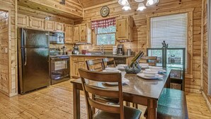 Une cuisine rustique aménagée dans une cabane en bois, comprenant un réfrigérateur, une cuisinière et une table à manger avec des chaises.