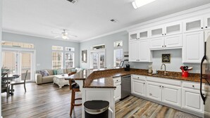 A spacious kitchen with white cabinetry, a granite countertop, and a dining area with a sofa and chairs.