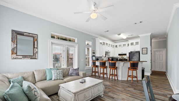 A spacious living room with a beige sofa, a white coffee table, and a dining area with a wooden table and chairs.