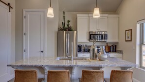 A kitchen with a central island, white cabinets, stainless steel appliances, and pendant lighting. - Peaceful | Clean | Get-a-way!  | Sunsets and Palms Casita (Washington)