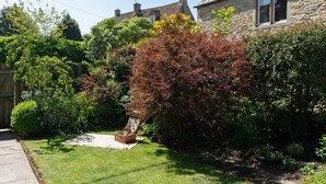 Une maison en pierre dotée d’un jardin bien entretenu, d’un espace aménagé pour pique-niquer et offrant une vue dégagée sur les environs.