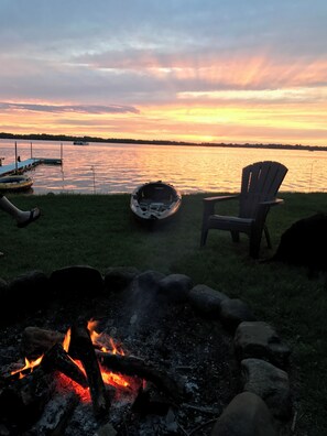 Un cadre idyllique au bord du lac, avec un foyer, un bateau et un fauteuil.