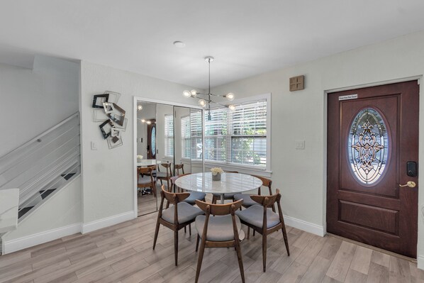 A dining area with a round table and chairs, a staircase, and a door with a stained glass design. - Sarasota Paradise Home Near Siesta Key Beach and IMG Academy (Sarasota)