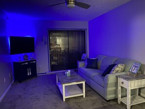 A living room with a flat-screen TV, a sofa, a coffee table, and a small side table. - Let the fun begin ππββοΈπ<br>Located between both beaches (Rehoboth)