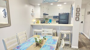 A dining area with a wooden table, four chairs, and a colorful table runner. - Let the fun begin 🏖🏊‍♀️😁<br>Located between both beaches (Rehoboth)