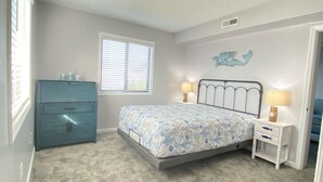 A bedroom with a bed, a dresser, a nightstand, a lamp, and a window. - Let the fun begin 🏖🏊‍♀️😁<br>Located between both beaches (Rehoboth)