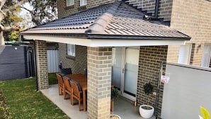 Une maison dotée d’un patio couvert, d’une façade en briques et d’une pelouse.