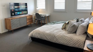 Une chambre à coucher avec un lit, une télévision, un bureau et une chaise.