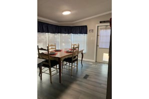 Enjoy meals in this dining area with a table and four chairs, set with plates, cutlery, and a napkin.