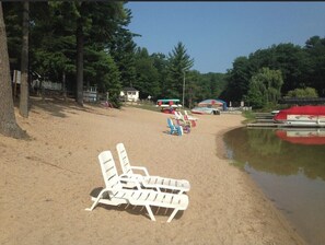 A sandy beach with lounge chairs and a small dock area.