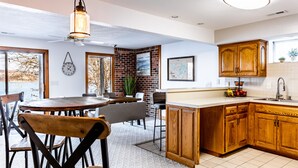 A kitchen with wooden cabinets, a dining area with a table and chairs, and a view of the outdoors. - Stunning Lake Front Home - Zero Entry Water Access (Sunrise Beach)