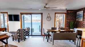A dining area with a view of the water, a ceiling fan, and a brick wall. - Stunning Lake Front Home - Zero Entry Water Access (Sunrise Beach)