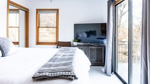 A bedroom with a large bed, a TV, and a view of the outdoors. - Stunning Lake Front Home - Zero Entry Water Access (Sunrise Beach)
