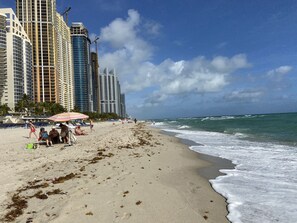 A beach with high-rise buildings in the background, sandy shore, and ocean waves. - 3BR Condo in Sunny Isles Beach (Sunny Isles Beach)