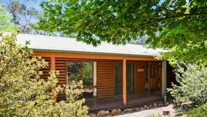 Eine Holzhütte mit Veranda, großen Fenstern und einer überdachten Terrasse.