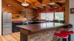 Eine moderne Küche mit Holzbalken, einer Kücheninsel aus Ziegelstein, Edelstahlgeräten und roten Barhocker.