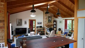 Ein gemütliches Wohnzimmer mit Kamin, Holzbalkendecke und einem großen Fernseher.
