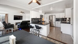 A modern kitchen with white cabinets, a black countertop, and stainless steel appliances. There is a dining area with a black table and chairs, and a ceiling fan above. - Beautiful house close to San Diego Zoo, Sea World, Coronado (Chula Vista)