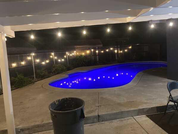 Una piscina de borde curvo, rodeada por una solana de hormigón.