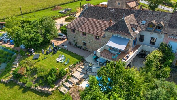A stone house with a large patio, a swimming pool, and a view of the surrounding countryside. - Gîte 12 per (Vers)