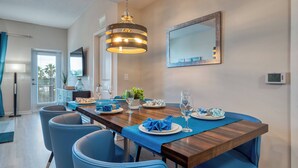 Un coin repas avec une table en bois, des chaises à l’assise rembourrée de couleur bleue et un luminaire suspendu.