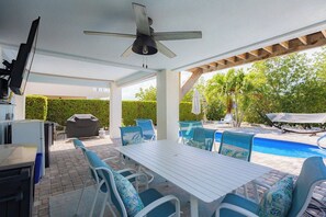 Un patio al aire libre con piscina, mobiliario y ventilador de techo.