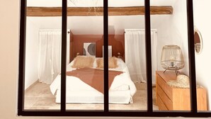 Un dormitorio con una cama, una lámpara colgante, una mesita de noche de madera y un espejo en la pared.