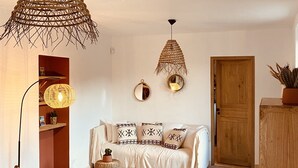 Una sala de estar acogedora con un sofá, dos sillones de mimbre y un mueble de madera.