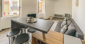 A modern kitchen with a central island, bar stools, and a hanging light fixture.