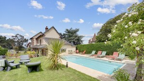 Um quintal com piscina, móveis de exterior e uma casa.