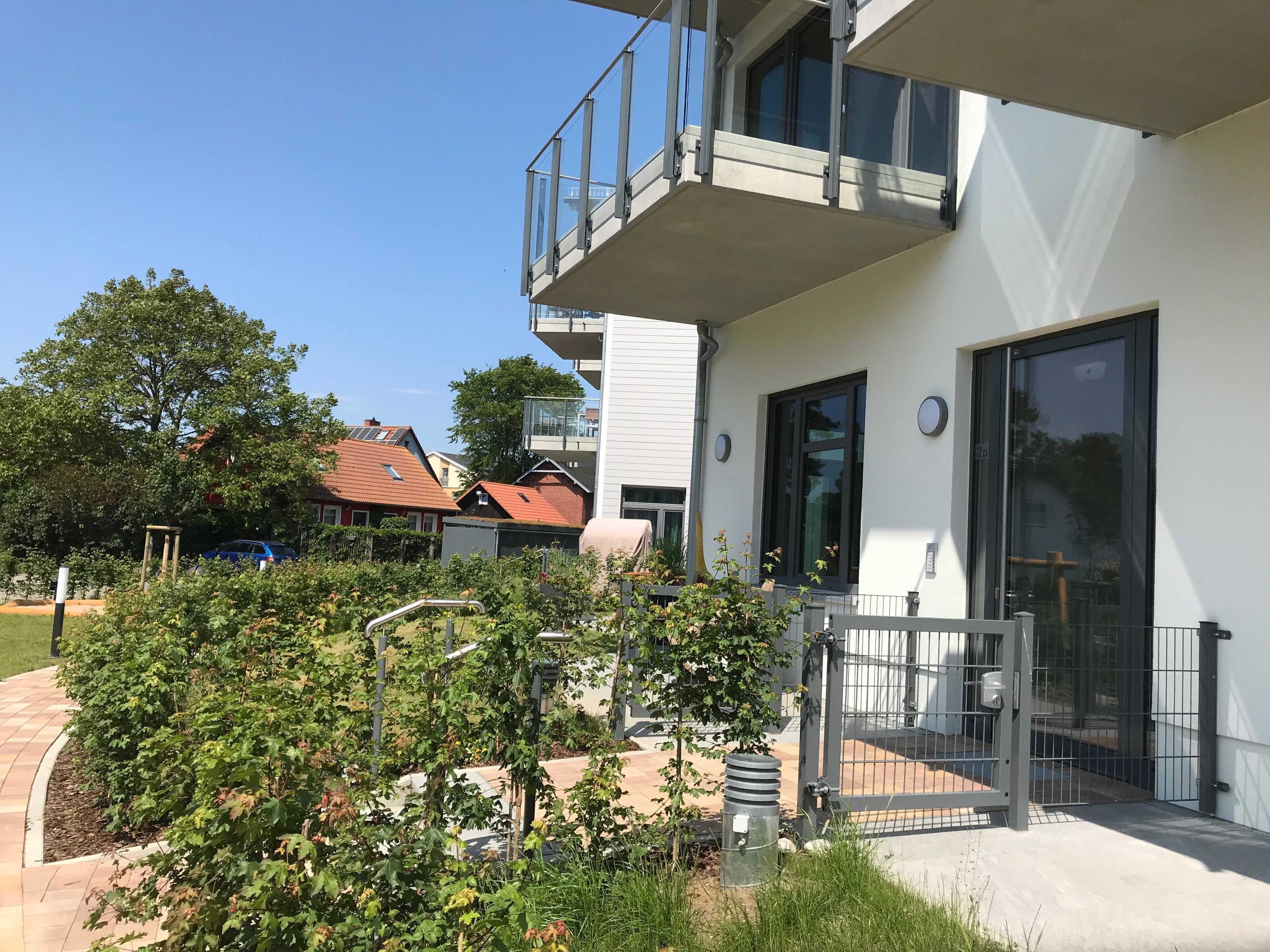En moderne bygning med balkon, lukket indgang og velplejet have.
