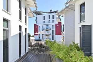 A modern building with a balcony featuring outdoor furniture and a covered area. - Ostseeherz, Deutschland (Glowe auf Rügen)