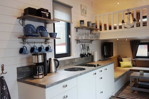A compact kitchen with white cabinets, a coffee maker, and blue-patterned dishes. - Tiny House mooring at the Ostseecamp Graal-Müritz :) - Tinyhouse Anchorage (Graal-Müritz)