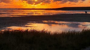 A sunset over a flat landscape with a body of water reflecting the sky. - Kapitänshuus, Deutschland (Nordstrand)