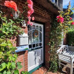 A brick house with a white door, a mailbox, and a bench.