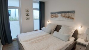 Une chambre à coucher avec un grand lit, une table de chevet avec une lampe et un tableau au mur.