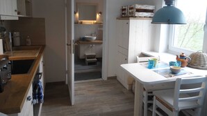 Ett kök med en vit bänkskiva, en diskho och ett fönster med utsikt över träd.